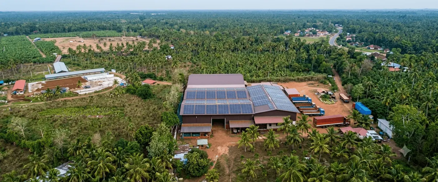 Aerial view of the Go Green Exports manufacturing complex in Bingiriya, Sri Lanka, with a solar array across the production roof and container trucks in the loading yard