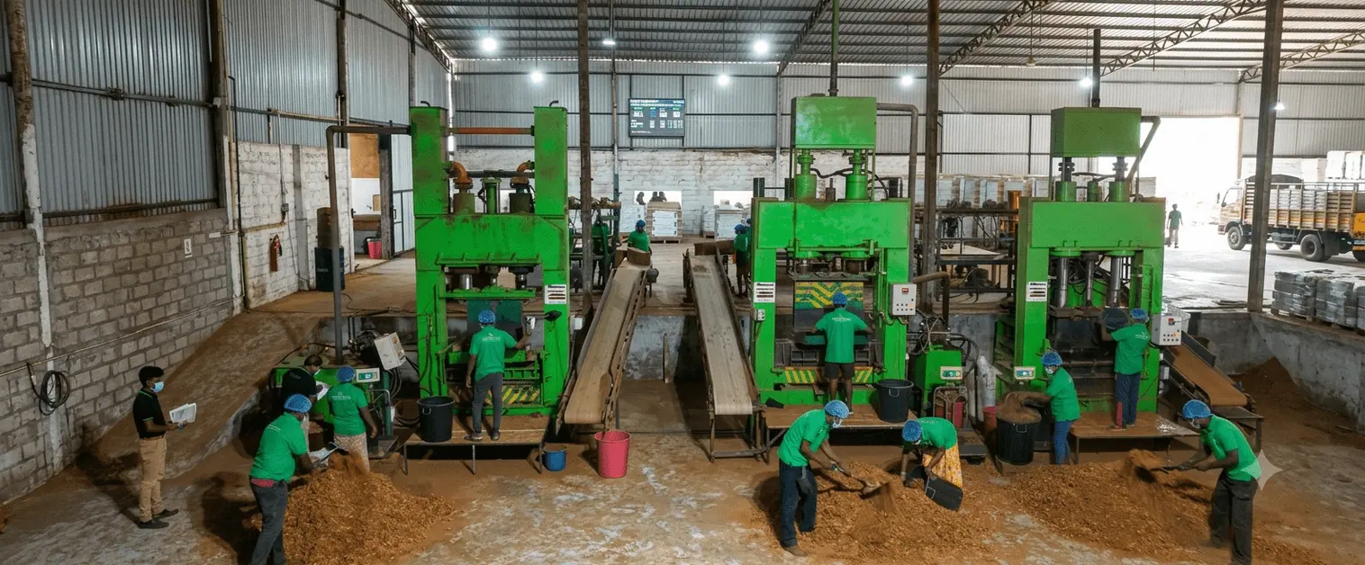 Production team operating hydraulic coco peat compression presses on the Go Green Exports factory floor